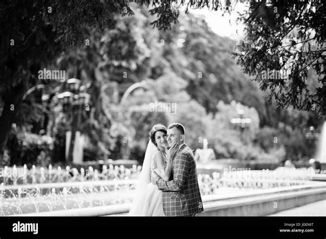 Attractive young wedding couple walking and posing in the park on a sunny day. Black and white ...
