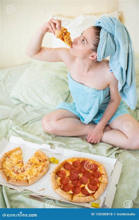 Cute Girl with a Towel on Her Head Eats Pizza in Bed. Young Woman Eating Fast Food in Bed ...