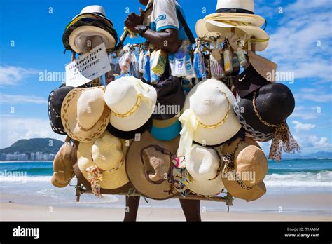 RIO DE JANEIRO - MARCH 21, 2017: A Brazilian beach vendor selling sun hats and sunscreen walks ...