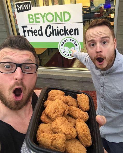 two men with their mouths open and one holding a tray of fried chicken in front of them