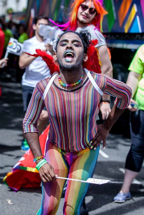 Someone celebrating Pride in London un a very colourful rainbow outfit. He is wearing it all ...