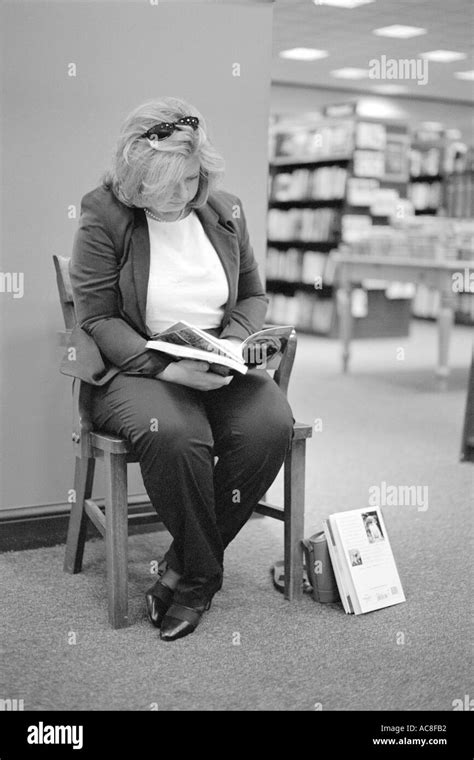 Woman sitting on chair reading in book store Stock Photo - Alamy