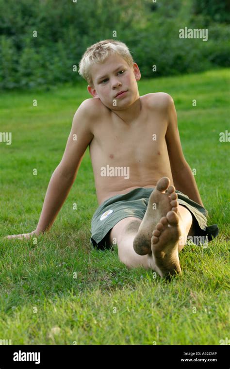 Portrait d'un jeune garçon aux pieds nus avec pieds sales assis dans l'herbe Photo Stock - Alamy