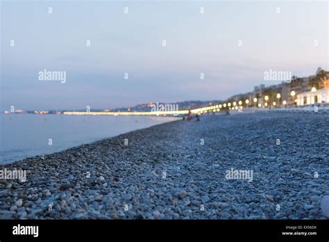 Illuminated beach promenade at night in Nice with blurred people playing in the background with ...