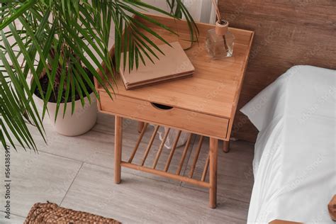 Wooden bedside table with books and reed diffuser in bedroom Stock Photo | Adobe Stock