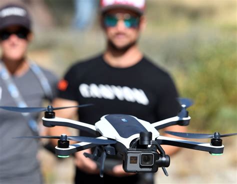 two men standing next to each other holding up a small black and white remote controlled flying ...