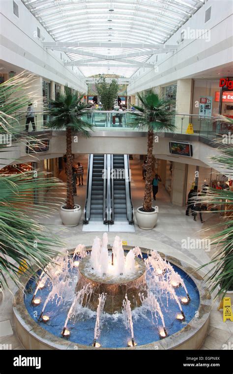 Interior of shopping mall with water fountain, escalators and skylight ...