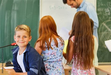 Smiling boy with friends studying in classroom Stock Photo | Adobe Stock