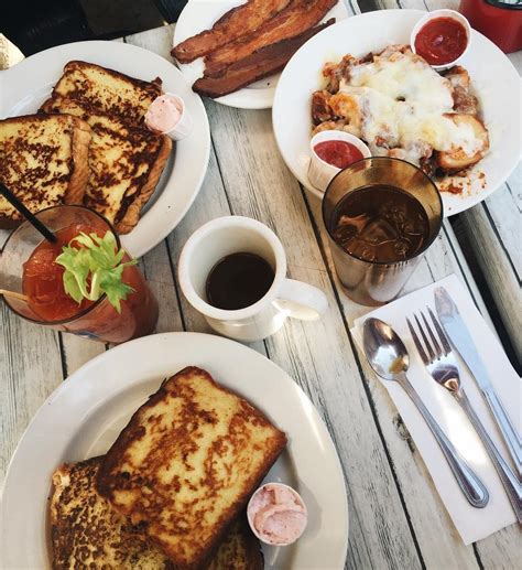 two plates with french toast, bacon and coffee on a wooden table next ...