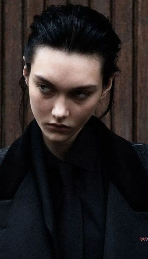 a woman with black hair wearing a dark suit and looking off to the side ...