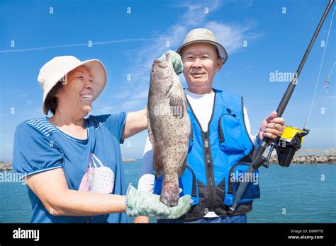 asian senior couple fishing and showing big grouper Stock Photo - Alamy