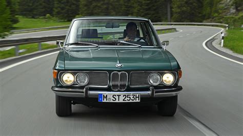 a green bmw is driving down the road