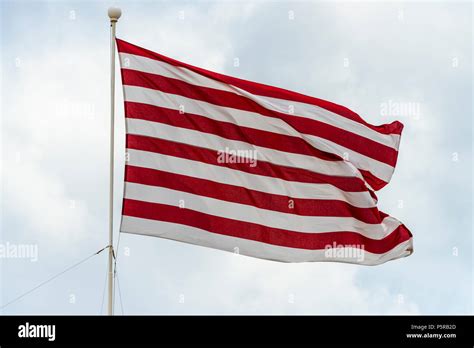 A red and white striped flag flying against a dull, overcast day.in Malta Stock Photo - Alamy