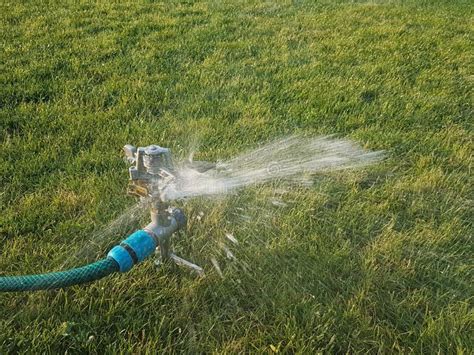 A Water Spray Irrigates the Green Grass Lawn. Irrigation System for Green Spaces. Taking Care of ...