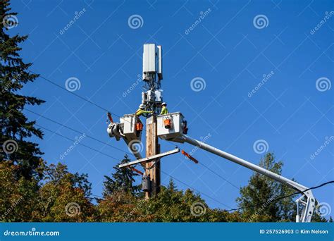 Two Linemen Working on a Wireless Communications Radio and Antenna Installation Using a Bucket ...