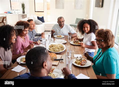 Three generation black family sitting at the table talking and eating dinner together, close up ...