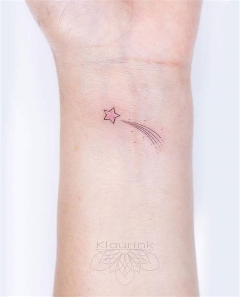 Minimalist shooting star tattoo on the wrist.