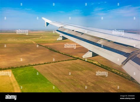 View of airplane wing, blue skies and green land during landing ...