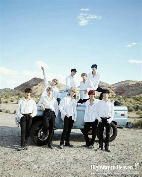 a group of young men standing next to an old car in the middle of nowhere