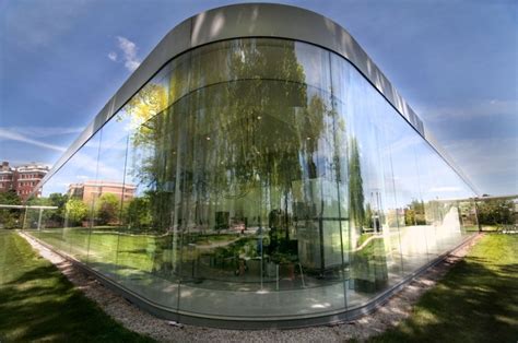 a large glass building sitting on top of a lush green field