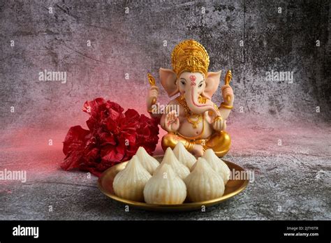 Idol of lord Ganesha with Modak Sweet Dish and flower. Ganesh chaturthi ...