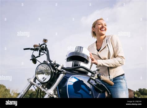 Happy female biker on motorcycle looking away Stock Photo - Alamy