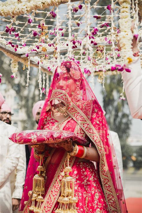 Photo of A sikh bride in a pink lehenga enters under a phoolon ki chaadar