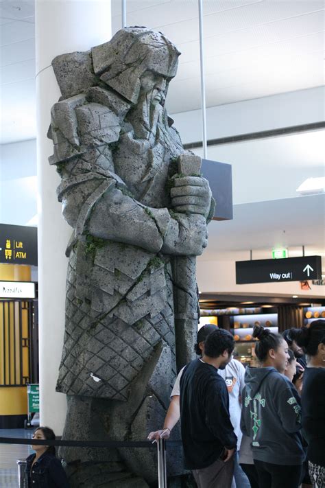 there is a statue that looks like a man holding a cane in the airport lobby