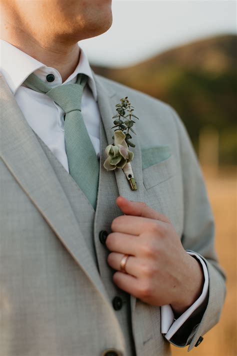 Groom with grey suit green tie and succulent boutonniere and rose gold ...