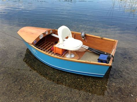 a small blue boat with a white seat on the water's edge, in shallow water