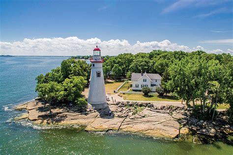 an island with a light house on it in the middle of water surrounded by ...