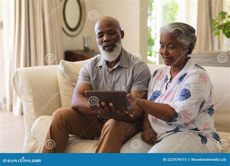 Senior African American Couple Sitting on Sofa Using Tablet and Smiling ...