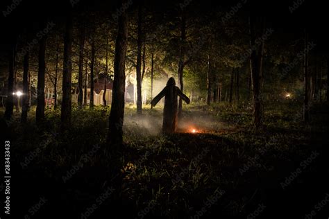 strange light in a dark forest at night. Silhouette of person standing ...