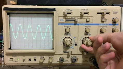 Electronics working with oscilloscope and sine wave shown on ...