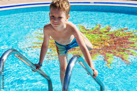 Happy kid playing in blue water of swimming pool. Little boy learning ...