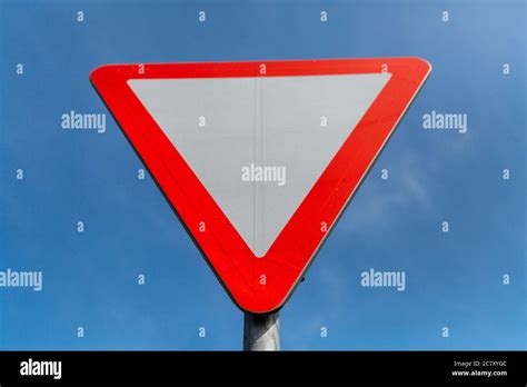 Road sign give way on blue sky background Stock Photo - Alamy