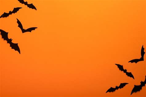 Premium Photo | Orange halloween background flock of black bats for halloween black paper bat ...