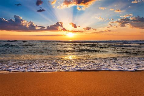 Colorful ocean beach sunrise with deep blue sky and sun rays ...