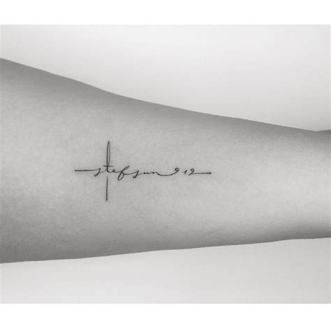 Lettering cross tattooed on the inner arm.