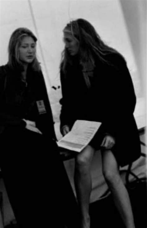 two women sitting next to each other in front of a white wall with ...