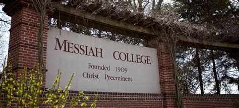 the sign for messiah college is posted in front of a brick wall and gate with vines growing over it