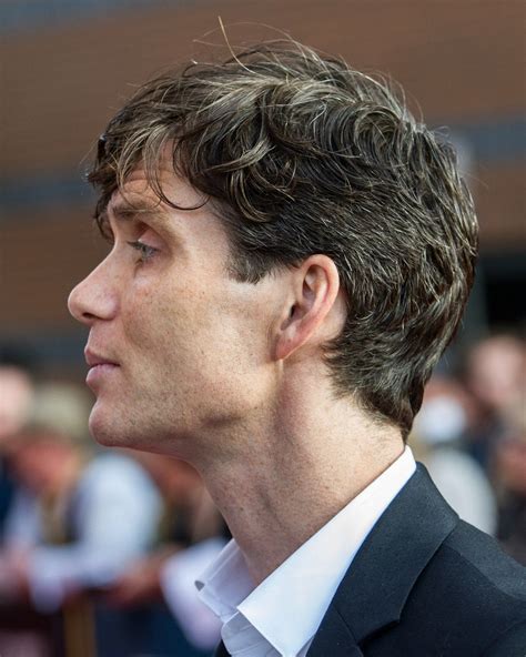 a close up of a person wearing a suit and tie with people in the background