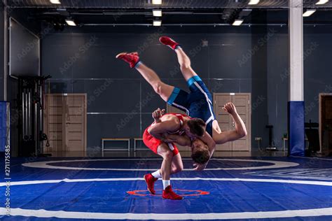 Two strong wrestlers in blue and red wrestling tights are wrestlng and ...