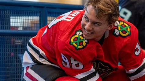 a young man sitting on top of a bench wearing a red jersey