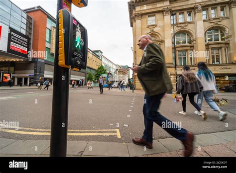 Pedestrians crossing the road at Market Street, Manchester. A puffin crossing displays the ...