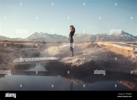 Side view of woman standing on rock at Mammoth Lake Hot Springs against ...