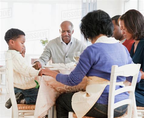 African American family praying before meal - Stock Photo - Dissolve