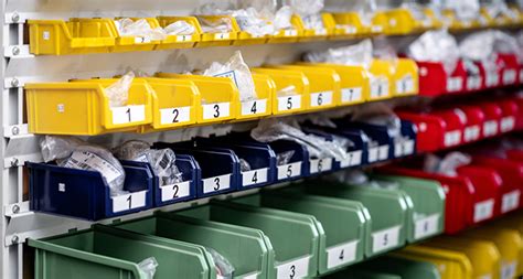 Hanging warehouse bins on a rail system with small parts and labels.