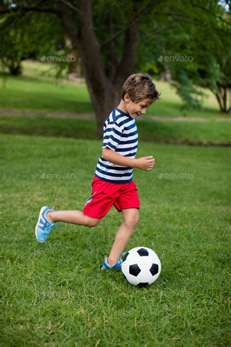 Boy playing football in park Stock Photo by Wavebreakmedia | PhotoDune