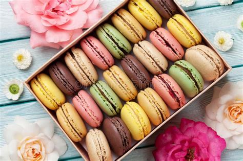 Photo about Colorful macaroons and rose flowers on wooden table. Sweet ...